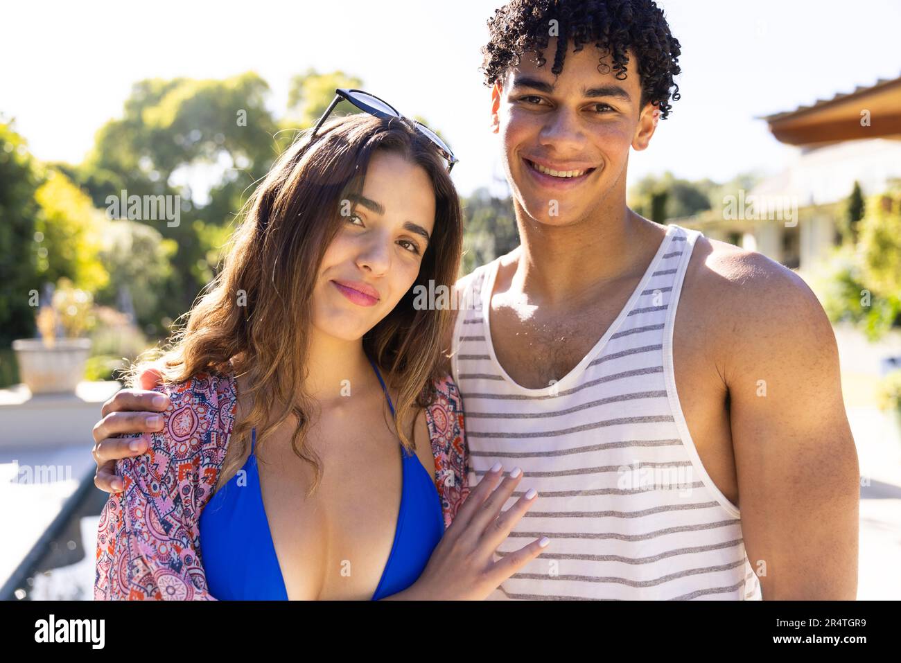 Portrait of smiling biracial young couple dressed in swimwear standing in yard against clear sky Stock Photo