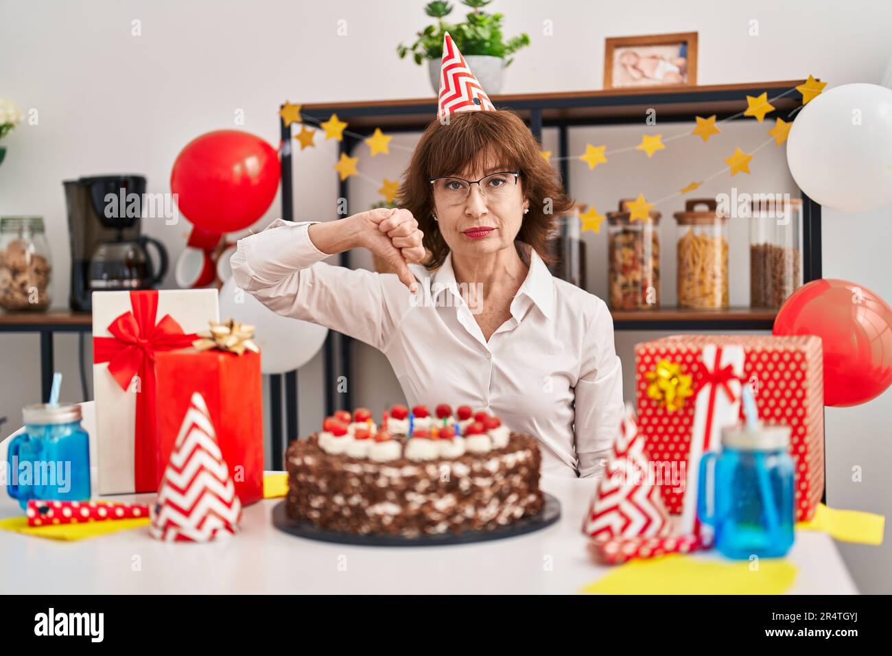 Middle age woman celebrating birthday holding big chocolate cake with ...