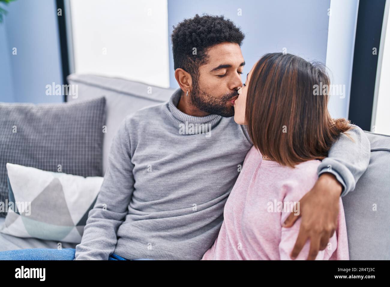 Man and woman couple kissing and hugging each other sitting on sofa at ...