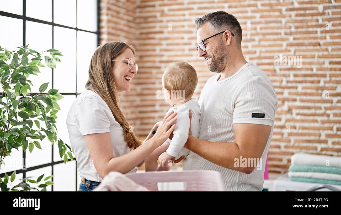 Family of mother, father and baby doing laundry at laundry room Stock Photo