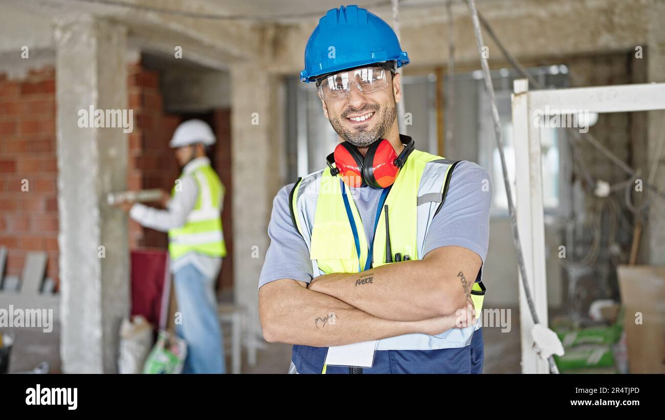 Two men builders standing with arms crossed gesture working at ...