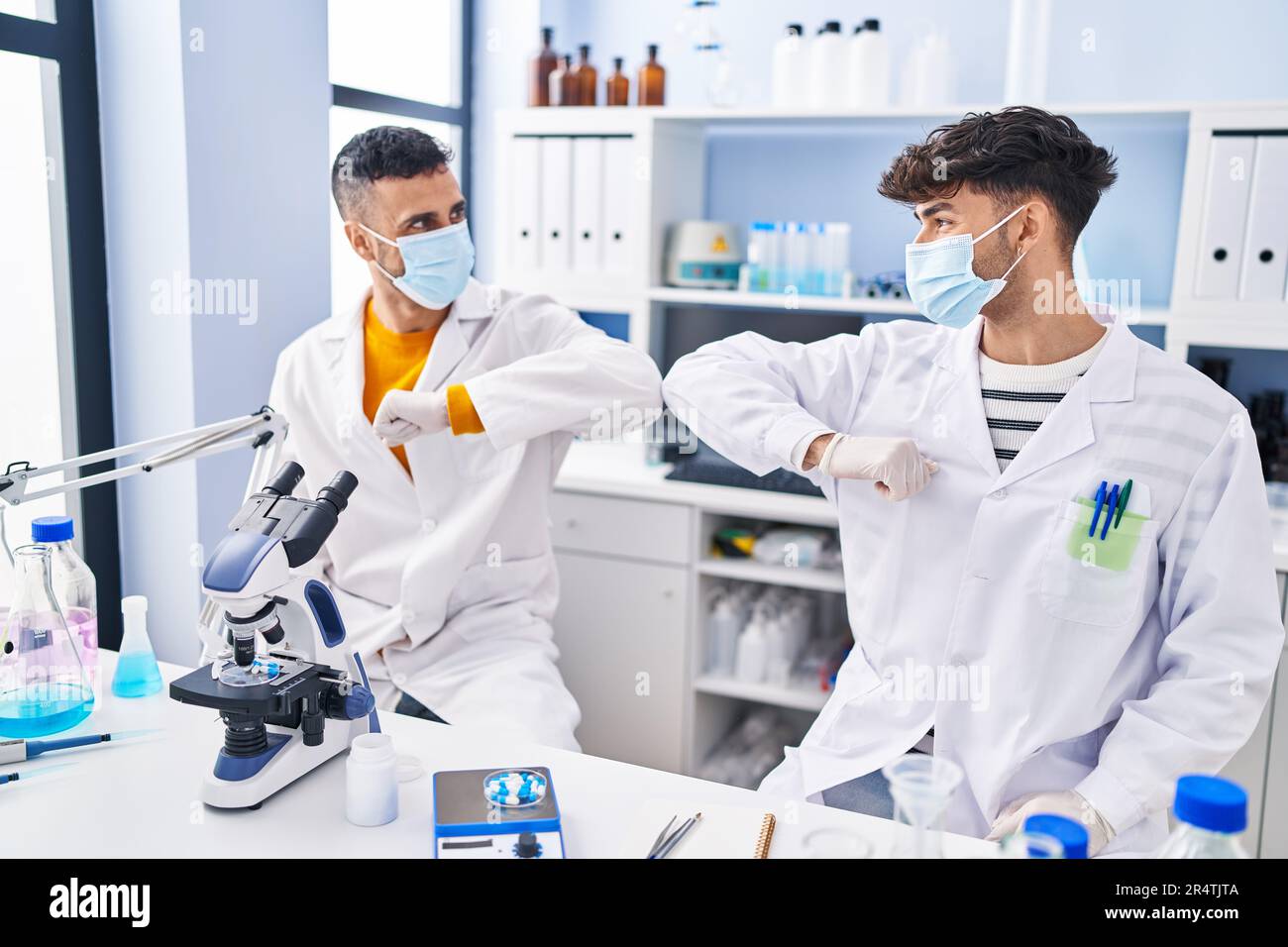 Two man scientists doing elbow greeting at laboratory Stock Photo