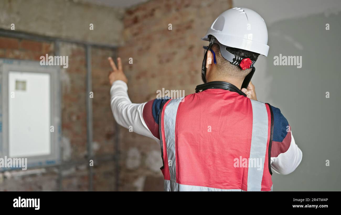 Young latin man builder talking on smartphone at construction site Stock Photo