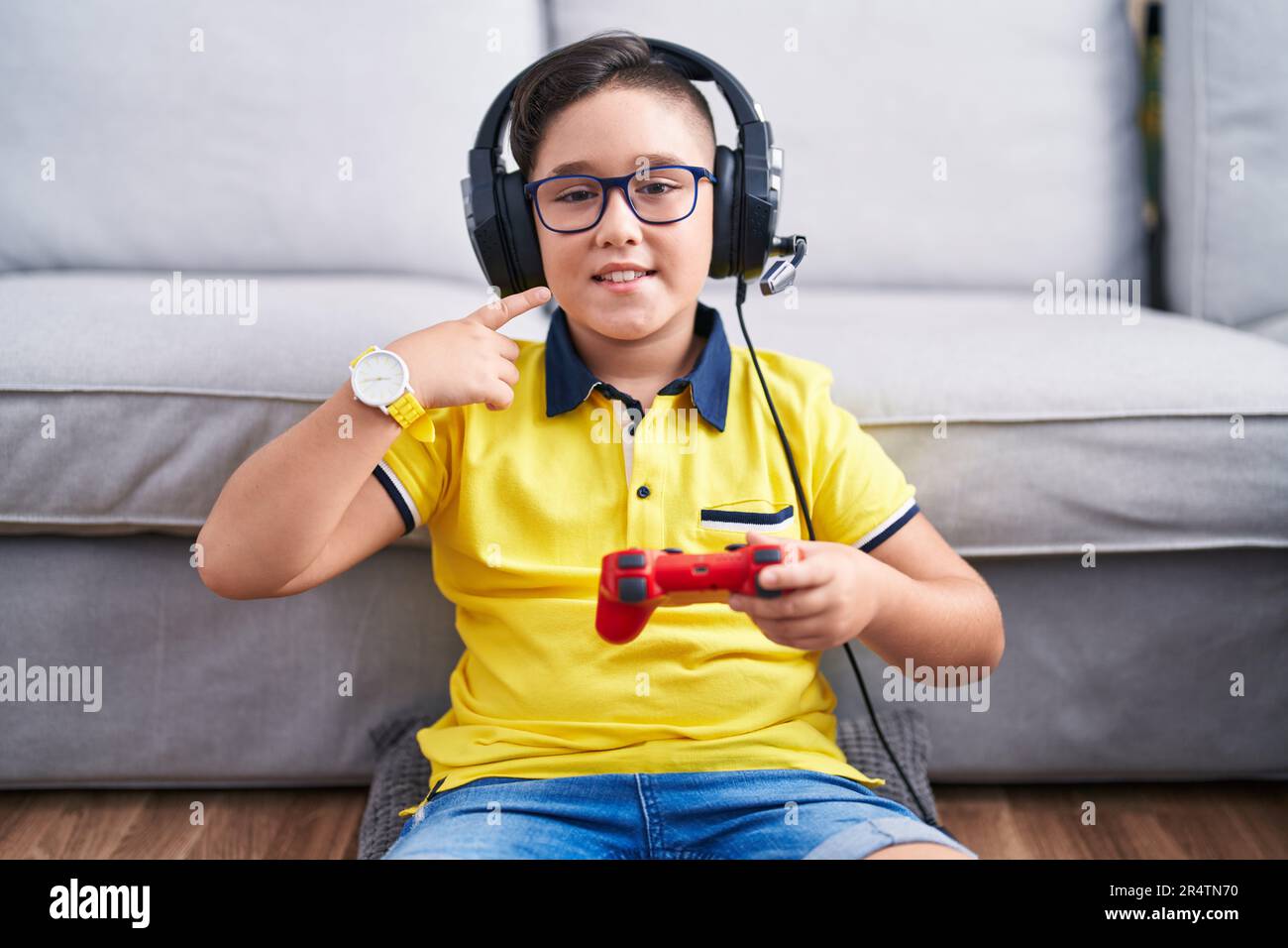 Kid Using Controller Young hispanic kid playing video game holding controller wearing ...