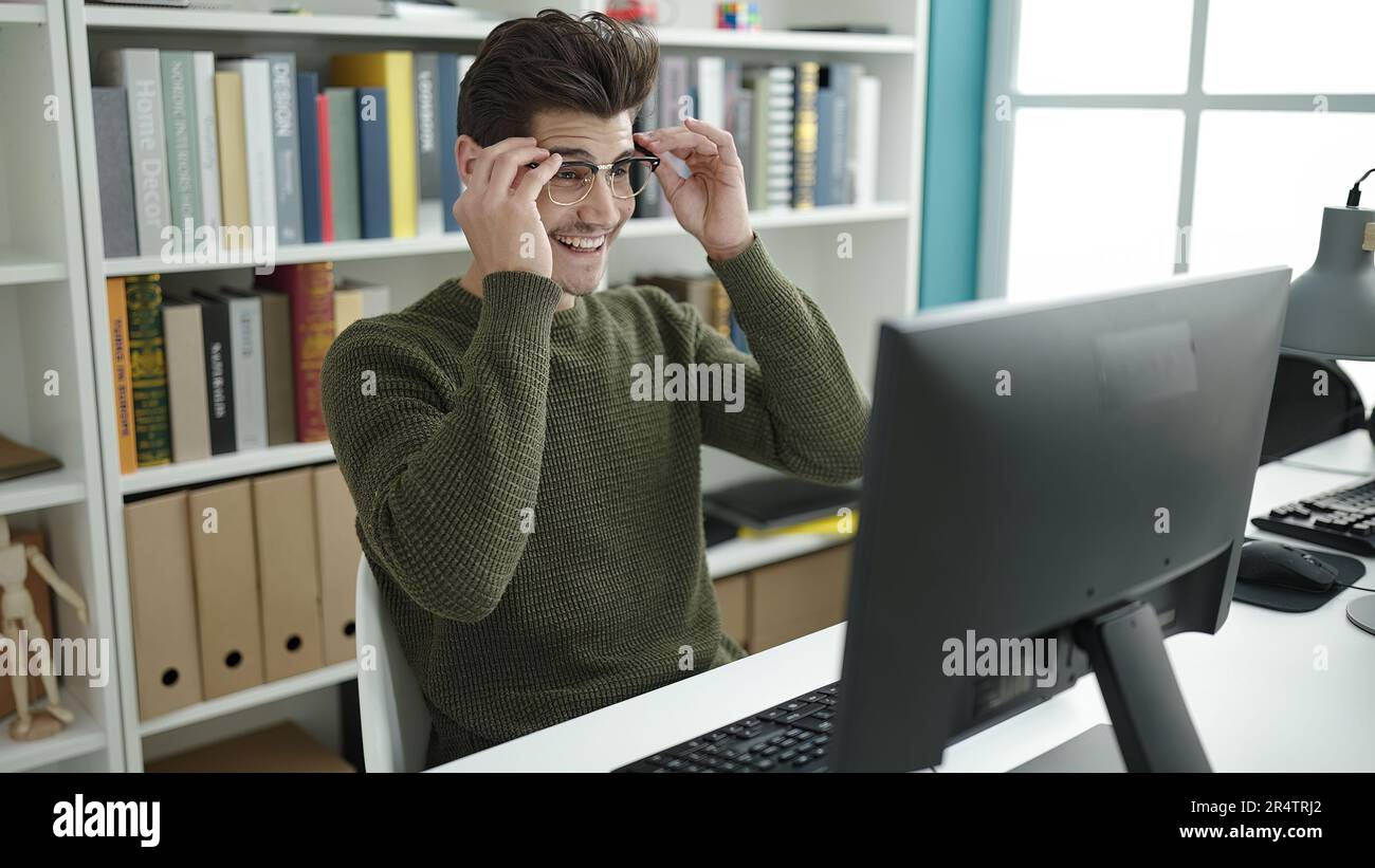 Young hispanic man student using computer studying at library ...