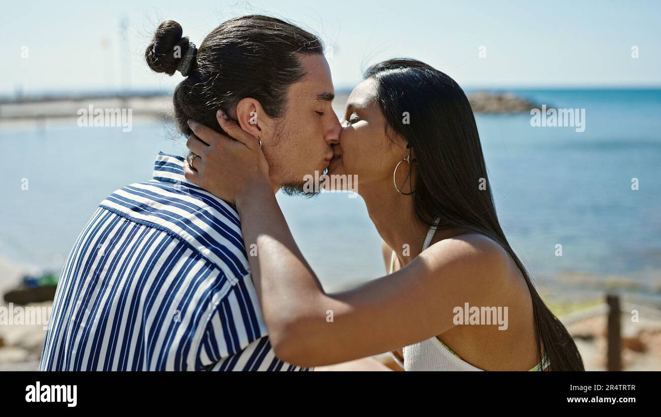 Man and woman couple sitting on bench kissing at seaside Stock Photo ...