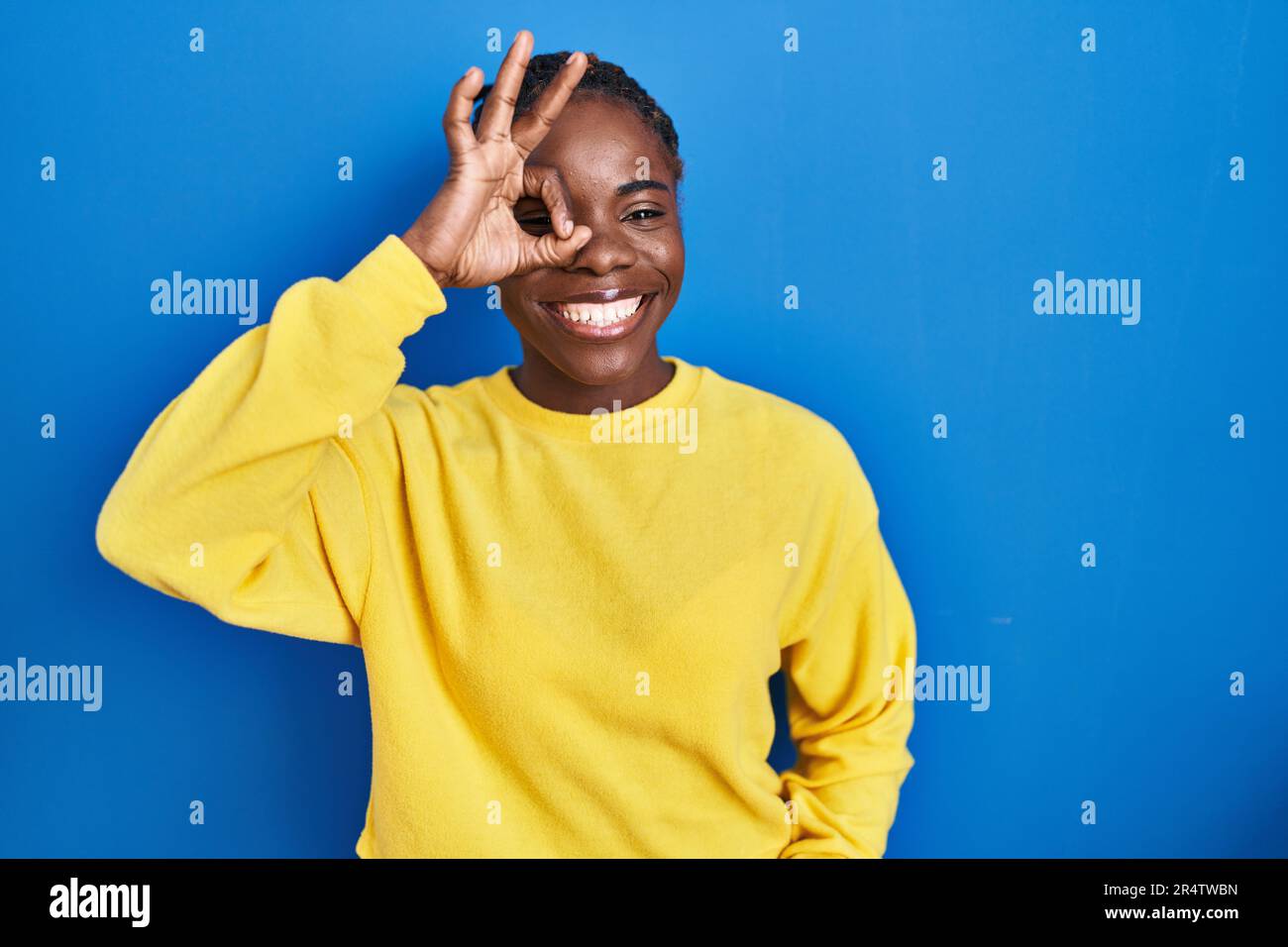 Beautiful black woman standing over blue background doing ok gesture ...