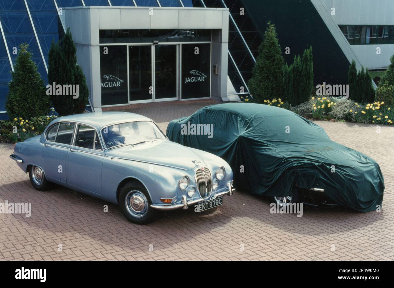 The new Jaguar car S-Type Saloon under wraps alongside the 1960's original car, UK 1999 Stock Photo