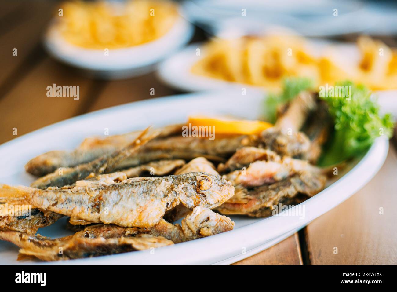 french fries and grilled fishes. fish and chips. Dish with Mullet Fish With orange. Fried fry small fishes Stock Photo