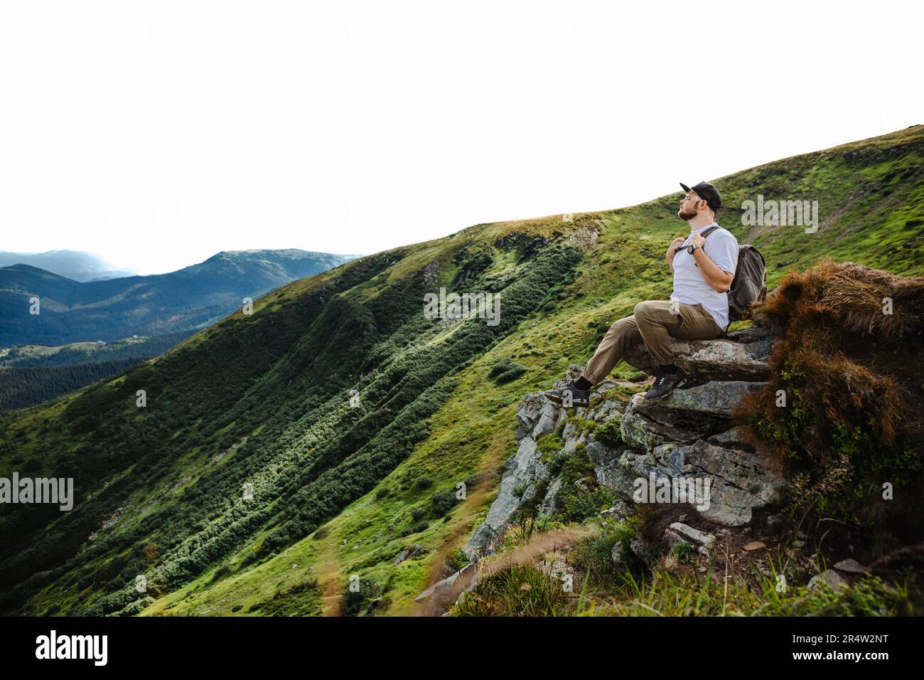 Man on top of a mountain sitting on a rock Stock Photo - Alamy