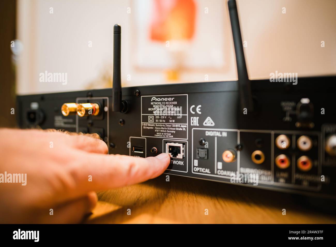 Frankfurt, Germany - Jan 30, 2023: Unboxing the Pioneer NC-50DAB Network CD Receiver, one person is indoors connecting it to technology via a RJ-45 ne Stock Photo