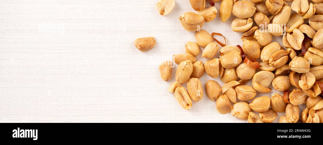 Spicy flavored peanut kernel spilling on white table background. Stock Photo