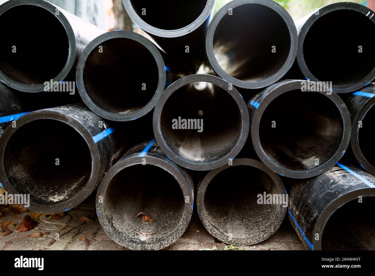 Pile of black HDPE pipes prepared for water transportation. Many plastic irrigation pipes made of high-density polyethylene Stock Photo