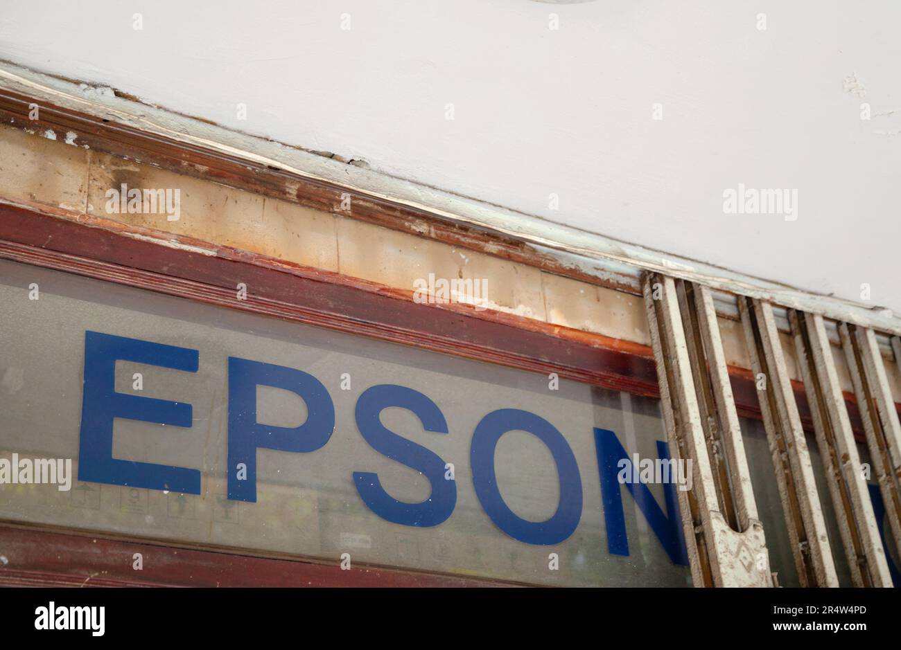 Ho Chi Minh City, Vietnam - May 22, 2023: Blue Epson logo in a window of a printer service center. Dirty old advertisement of a Japanese electronics m Stock Photo