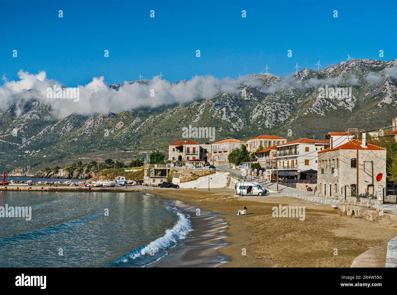 Village of Kotronas, Laconian Gulf harbor, wind turbines at Mount Sangias massif, Taygetos Mountains, Laconian Mani, Peloponnese region, Greece Stock Photo