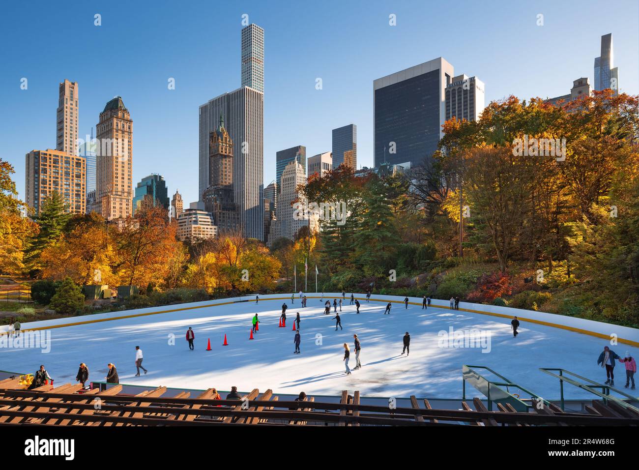Ice Rink Manhattan Wollman Rink at sunset in Central Park with view of skyscrapers. People ...