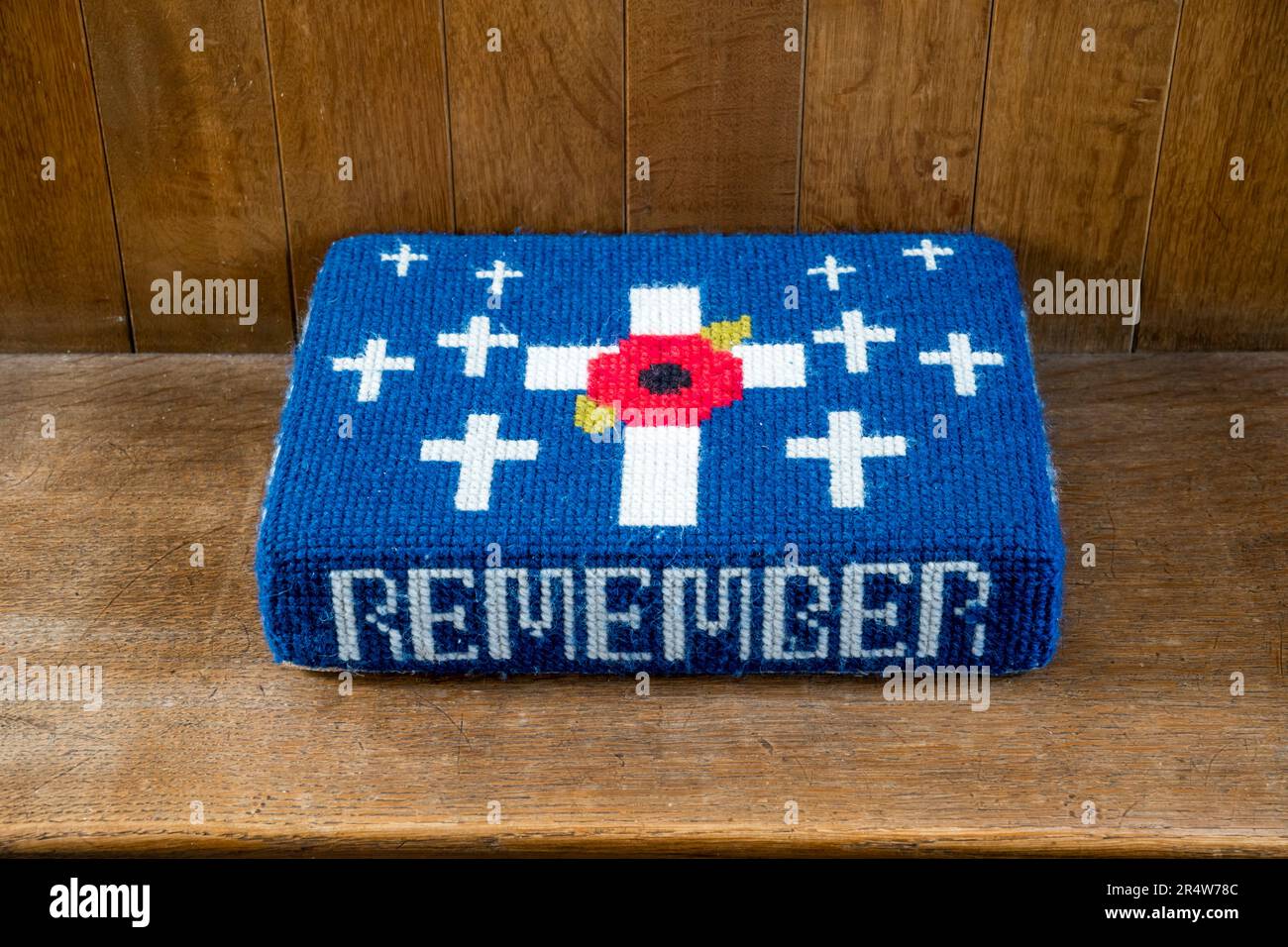 A remembrance themed church kneeler or hassock with a poppy and the word Remember. Stock Photo