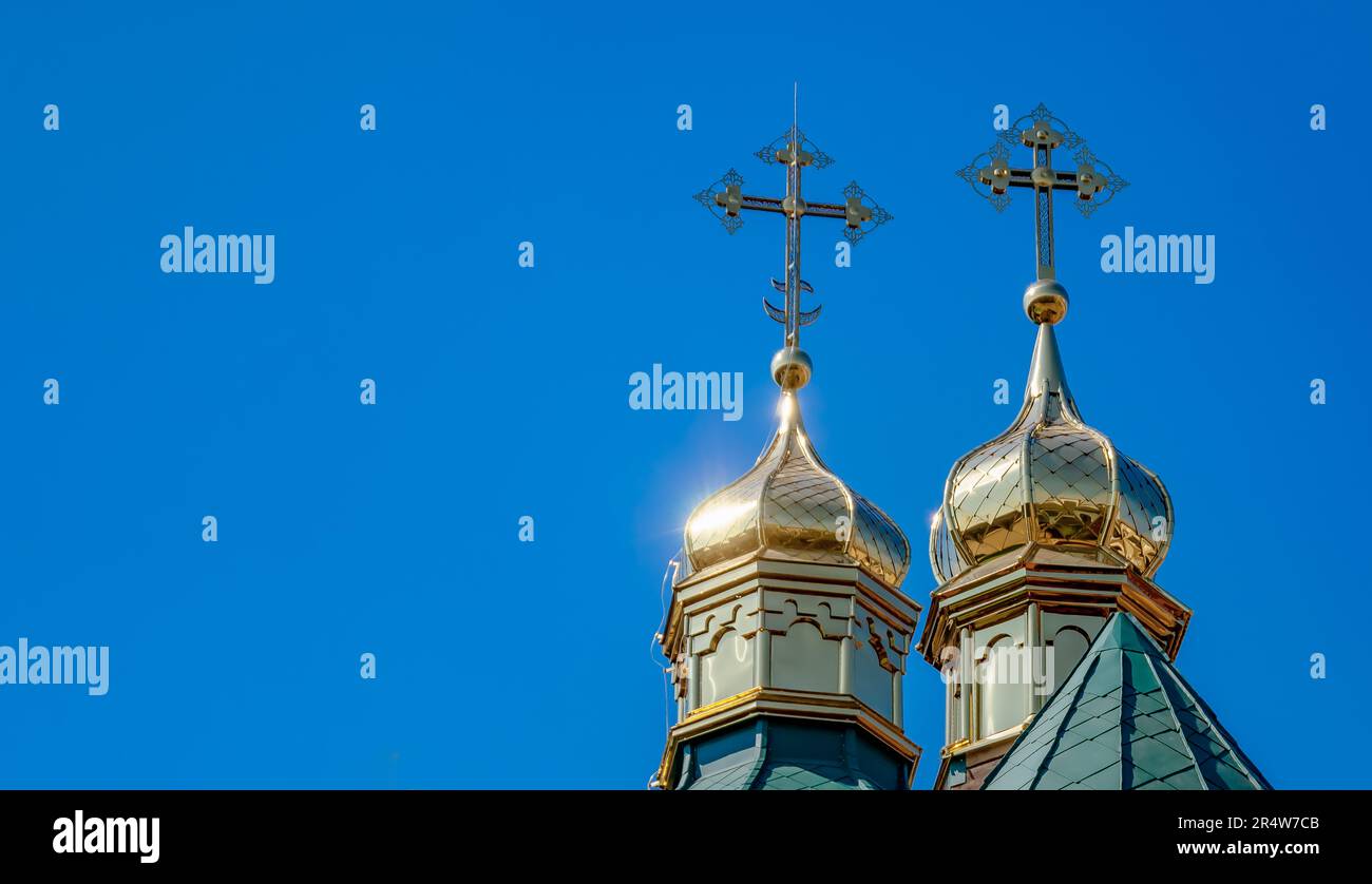 Two domes of church are covered with gold tin against a blue sky Stock Photo