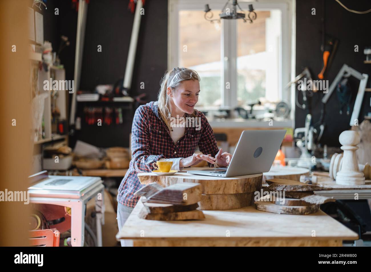 Female carpenter using laptop in a carpentry workshop Stock Photo