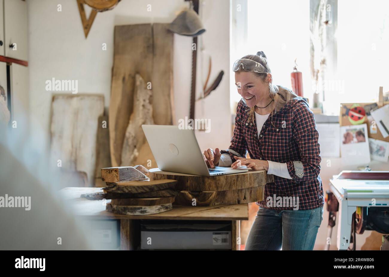 Female carpenter using laptop in a carpentry workshop Stock Photo