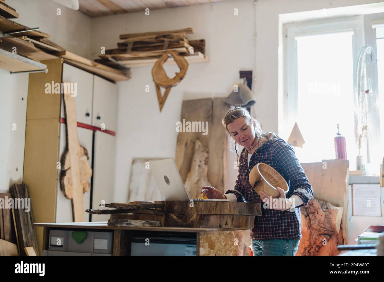 Female carpenter using laptop in a carpentry workshop Stock Photo
