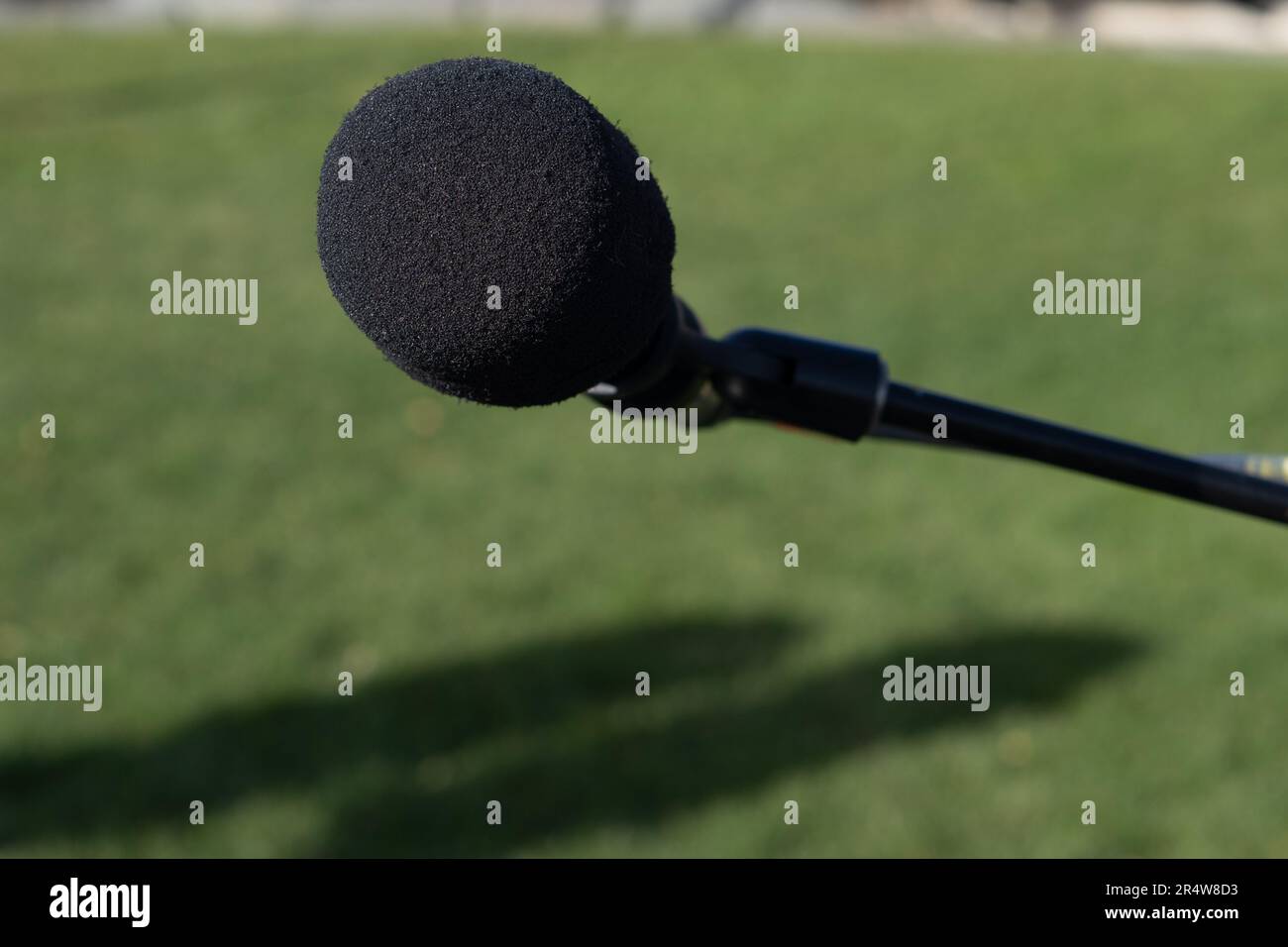 A black metal microphone on a stand. The round ball style mic is a classic for concerts and evening music sessions. The electronic equipment is a mic. Stock Photo