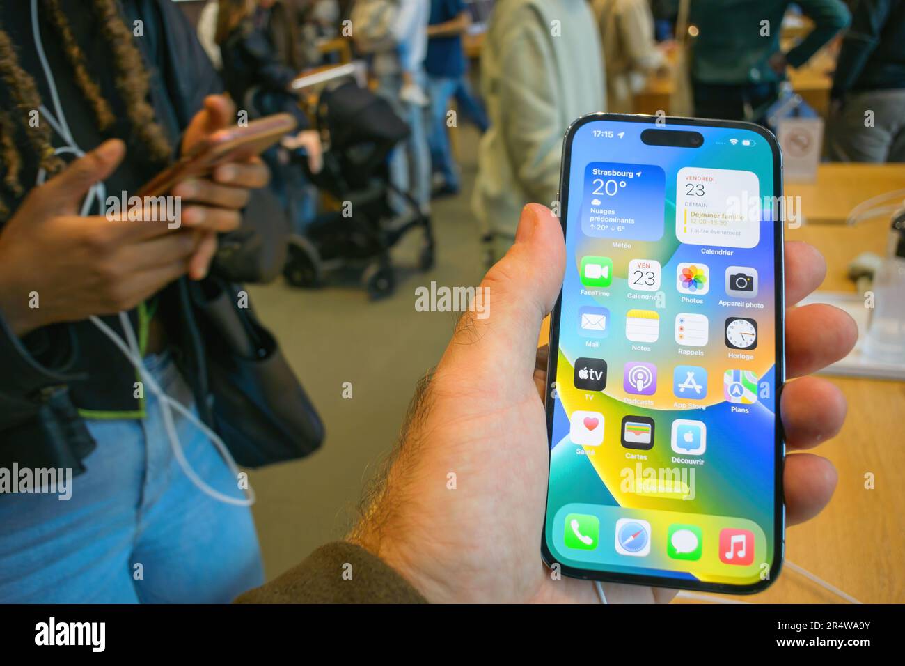 Paris, France - Sep 22, 2022: Customer inside apple store holding new smartphone with all apps on home screen - Apple launch new smartphone iPhone 14 Pro and iPhone 14 Pro Max - woman comparing phone nearby Stock Photo