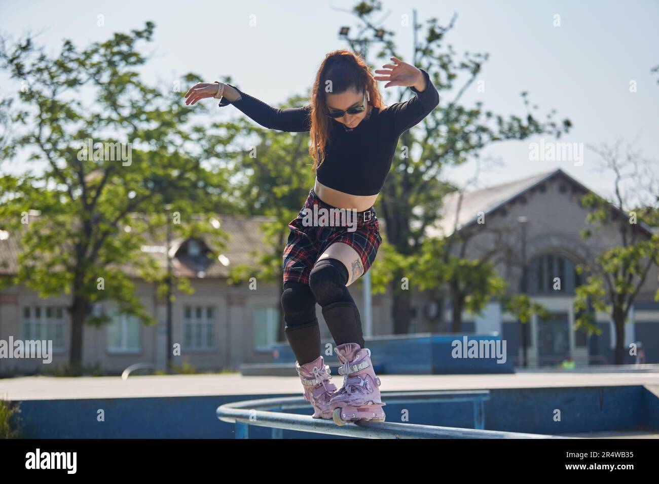 Cool young roller blader female grinding on a rail in a skatepark