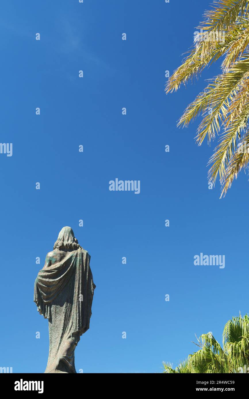 Statue of Jesus Christ the King looking towards blue sky, palm trees in
