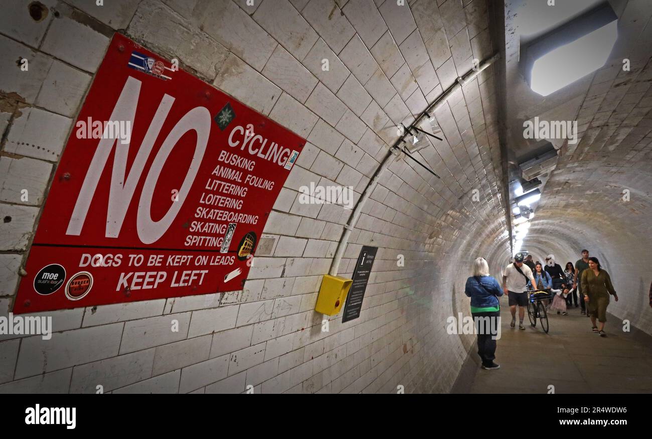 Interior of the Greenwich Foot Tunnel in London, showing pedestrians walking through the tiled underground passage beneath the River Thames Stock Photo