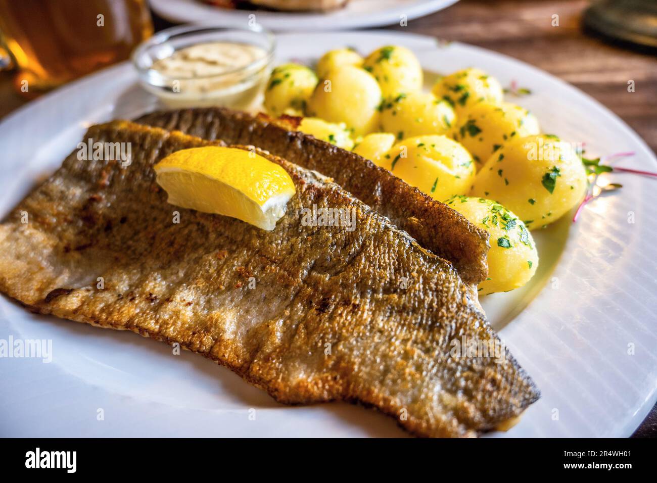 Golden fried zander fish with potato and tartar sauce, beer at restaurant table. Stock Photo
