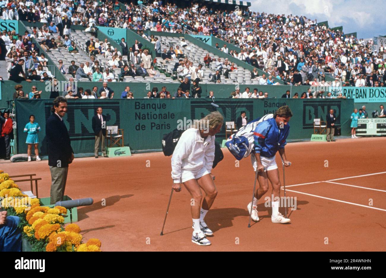 American players Vitas Gerulaitis and Jimmy Connors arriving on crutches before playing a men's doubles match at the French Open, in June 1989. Stock Photo