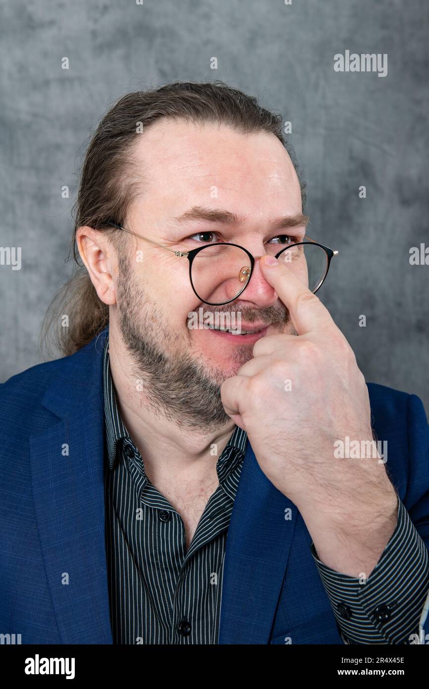 One man in a blue jacket adjusts his glasses Stock Photo
