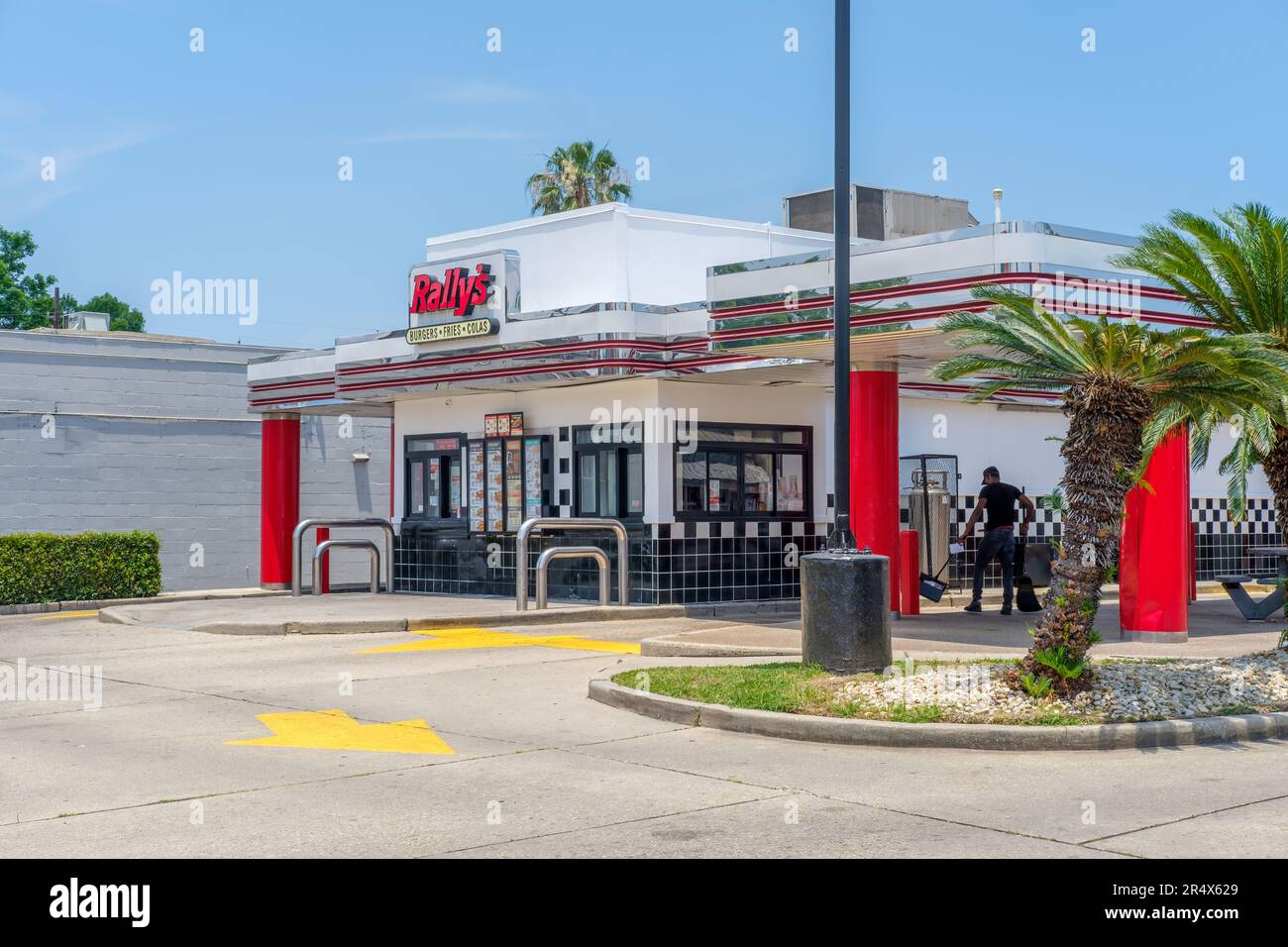 NEW ORLEANS, LA, USA - MAY 28, 2023: Rally's fast food restaurant with worker cleaning drive thru area Stock Photo