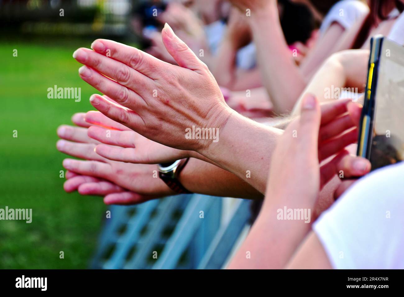 cheering and applauding blurred people at concert event. clapping female hands. wrist watch. performance and show of approval, praise and appreciation Stock Photo