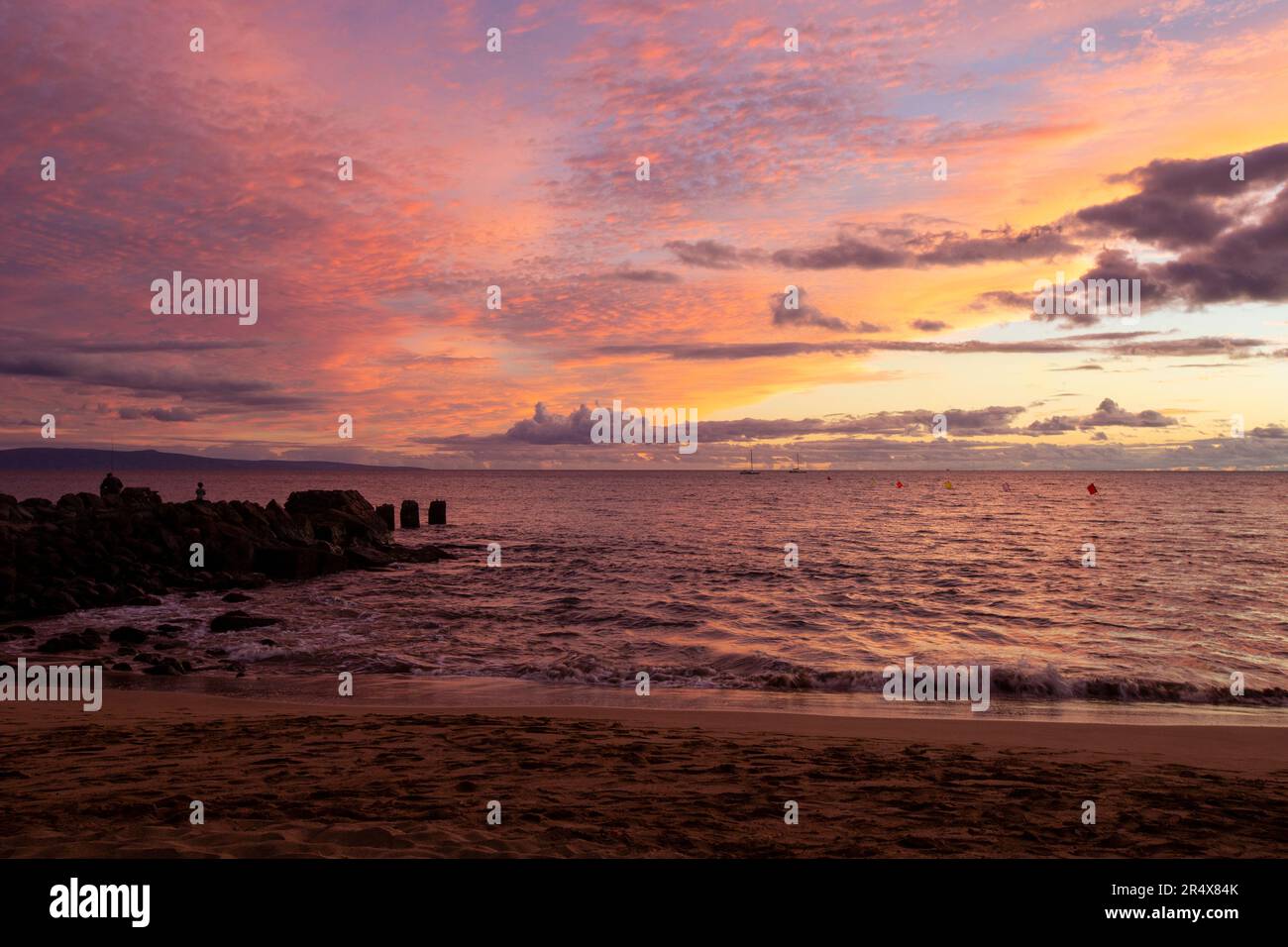 View from the beach of the silhouette of a rocky, pier groin jutting ...