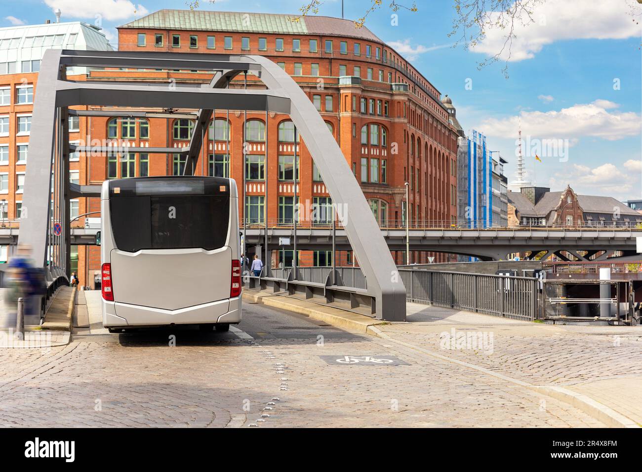 Back view of municipal public transport electric bus driving on paved road Elbe metal bridge in Hamburg old city center hafencity Germany. People Stock Photo