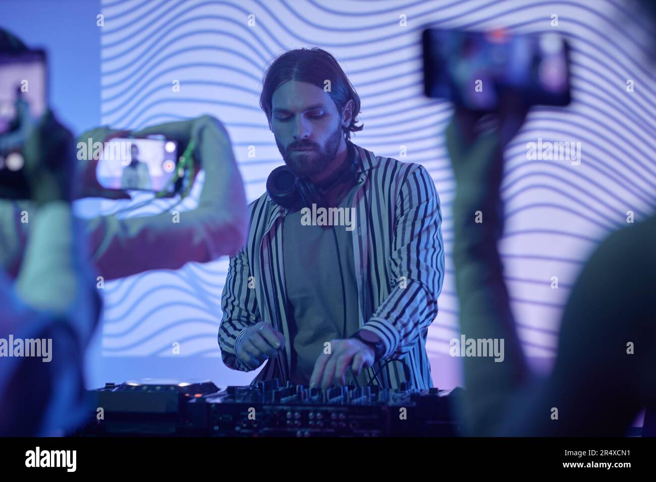 Portrait of long haired DJ by music station in neon lights entertaining  crowd at disco party Stock Photo - Alamy