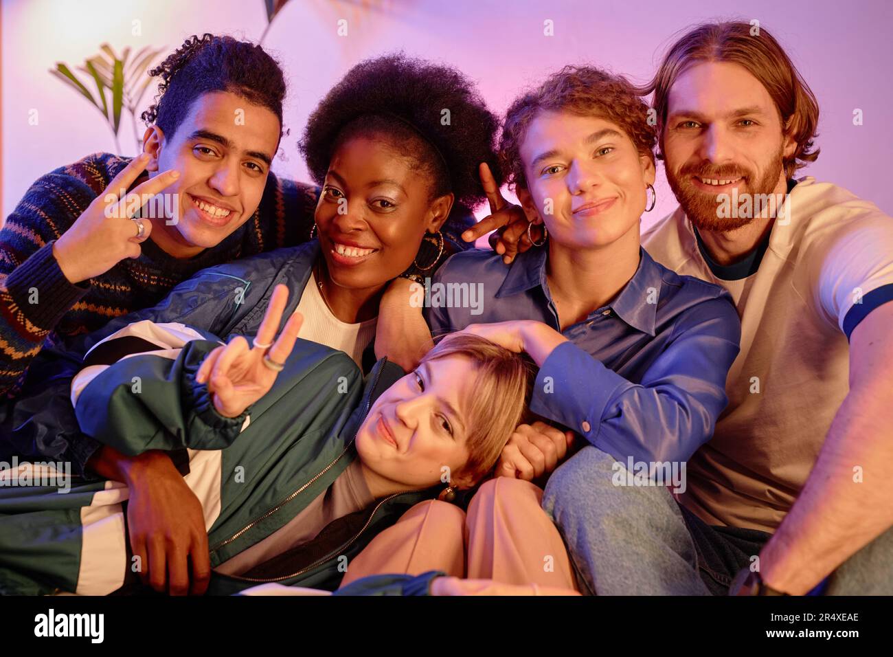 Diverse group of young people posing together at retro house party ...