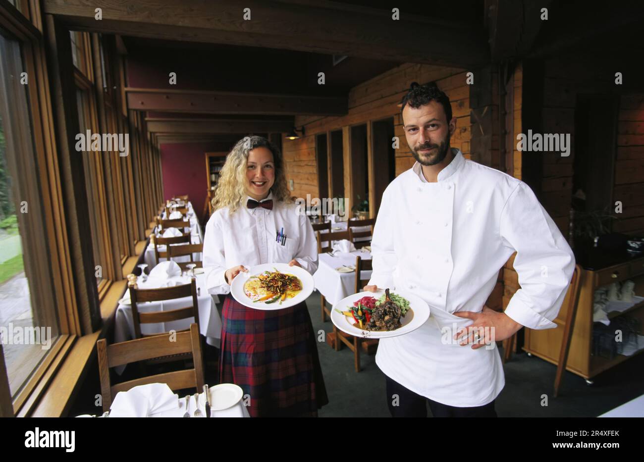 Chef and a waitress display plates of food in the lodge of Yoho National Park, BC, Canada; British Columbia, Canada Stock Photo
