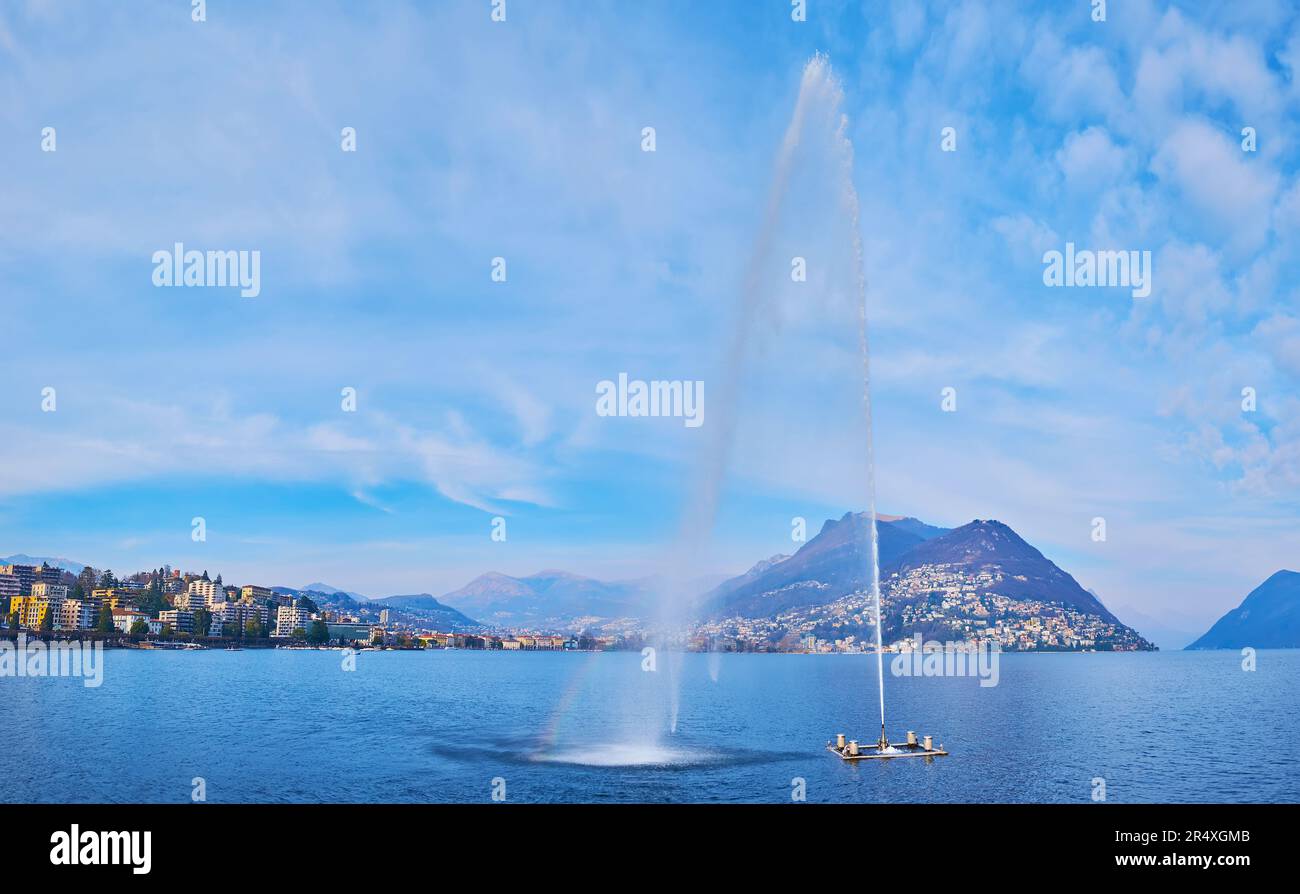 Lake Lugano embankment observes the famous fountain Getto d'Acqua (Water Jet on the bay of Lugano, Paradiso Water Jet) and Monte Bre in background, Lu Stock Photo