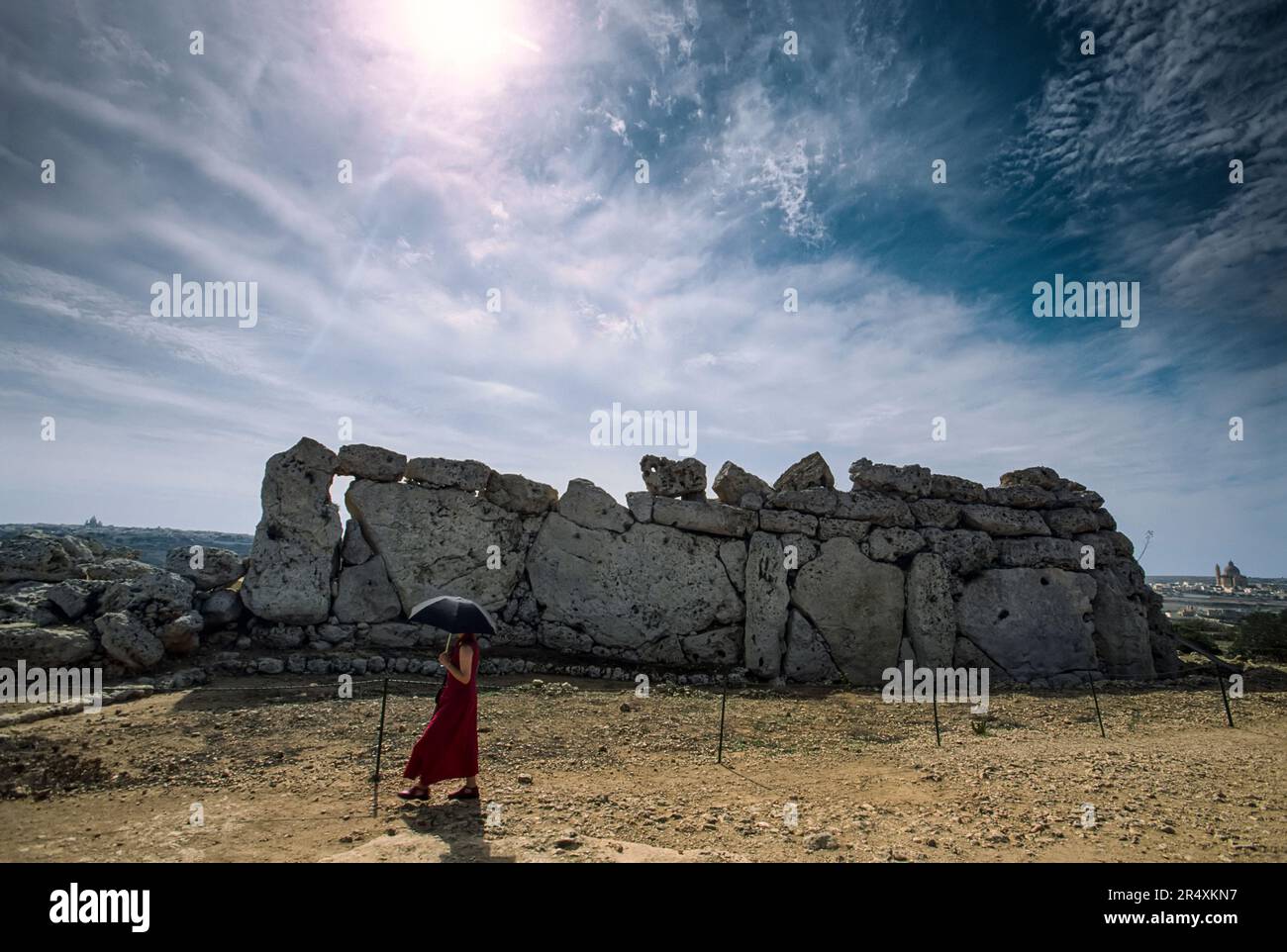 Woman with an umbrella walks past the neolithic temple of Ggantija; Ggantija, Gozo Island, Malta Stock Photo