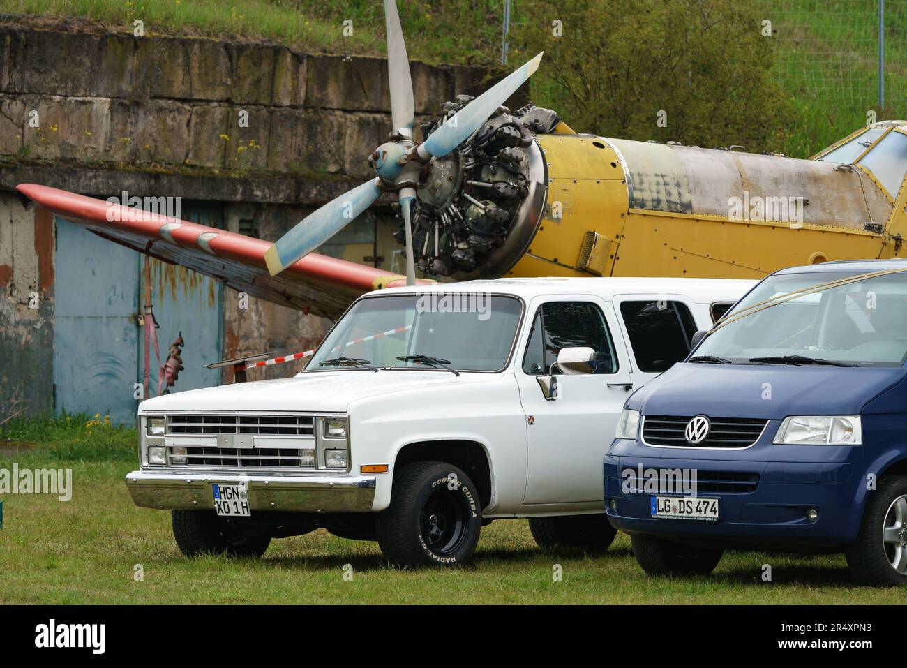 The full-size pickup truck Chevrolet Silverado C10, a modern VW Transporter against the background of the Soviet aircraft Antonov An-2. Stock Photo