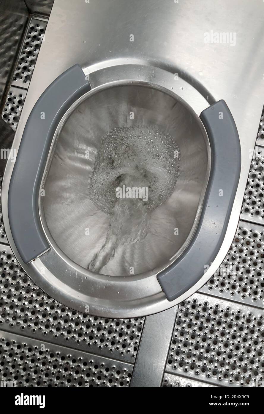 Sanitary metal urinal, toilet bowl in public bathroom with hygienic automatic water saving