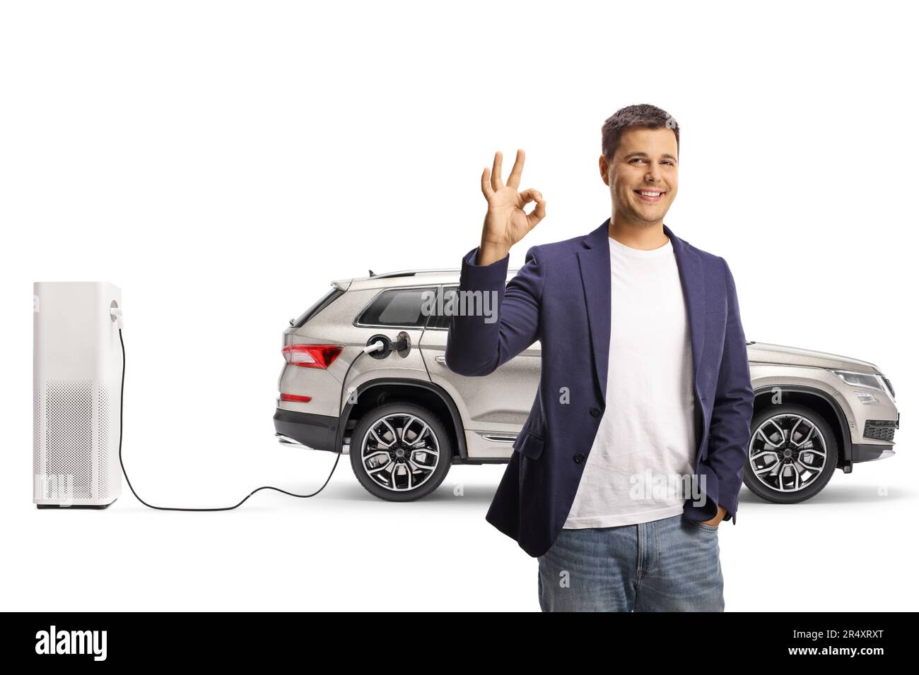 Young man gesturing ok sign in front of EV charging point isolated on white background Stock Photo