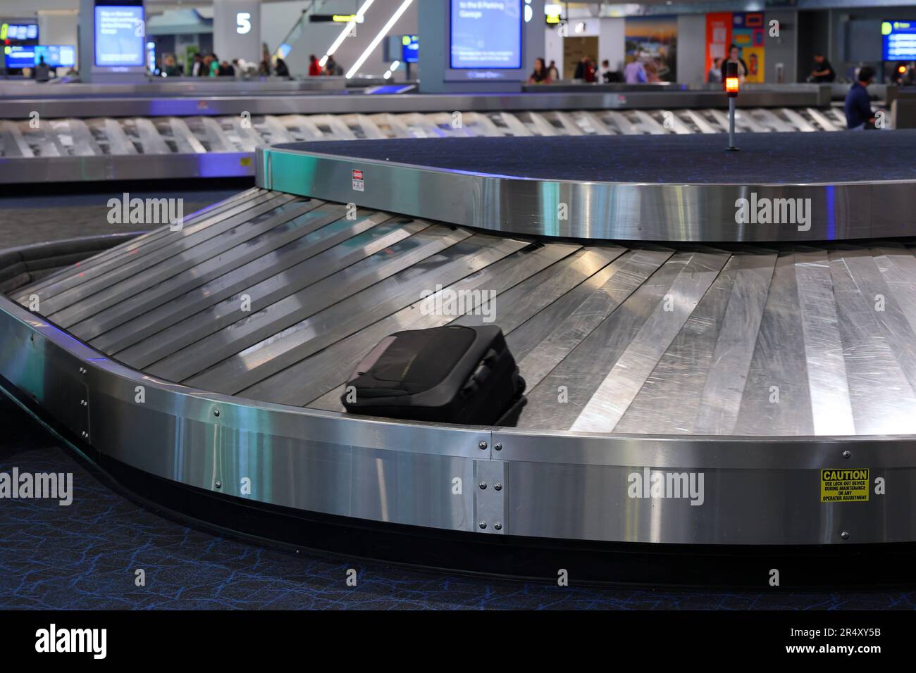 A suitcase on a luggage carousel at an airport arrivals baggage claim area. Stock Photo