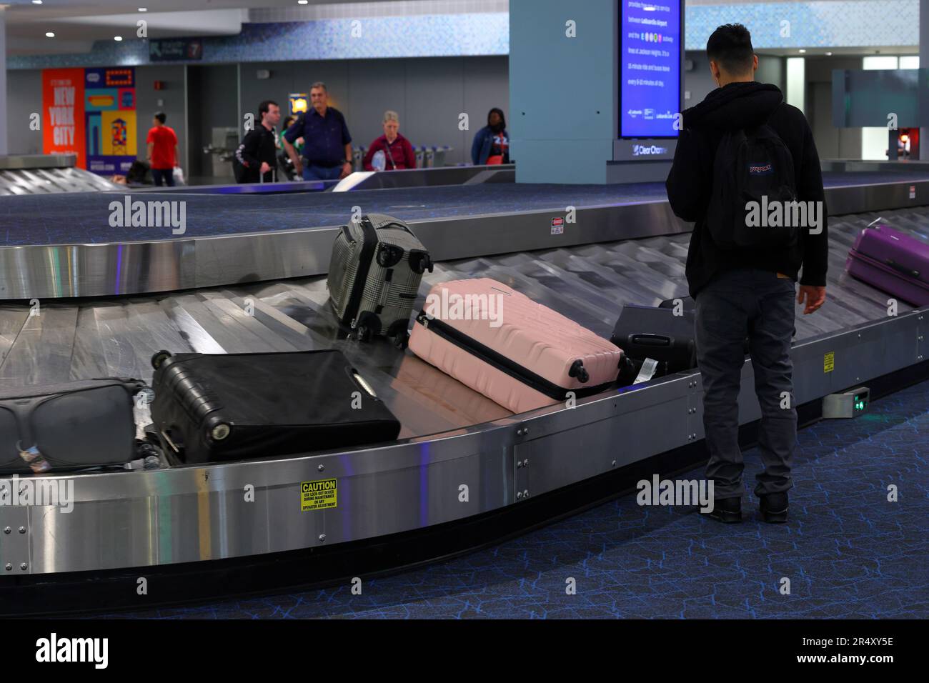 People waiting to pick up luggage from a baggage carousel at LaGuardia