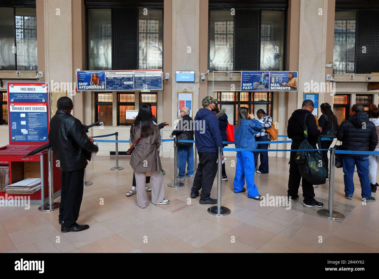 People queue inside the James A Farley Post Office in Midtown Manhattan, New York to buy stamps and other postal services. Stock Photo