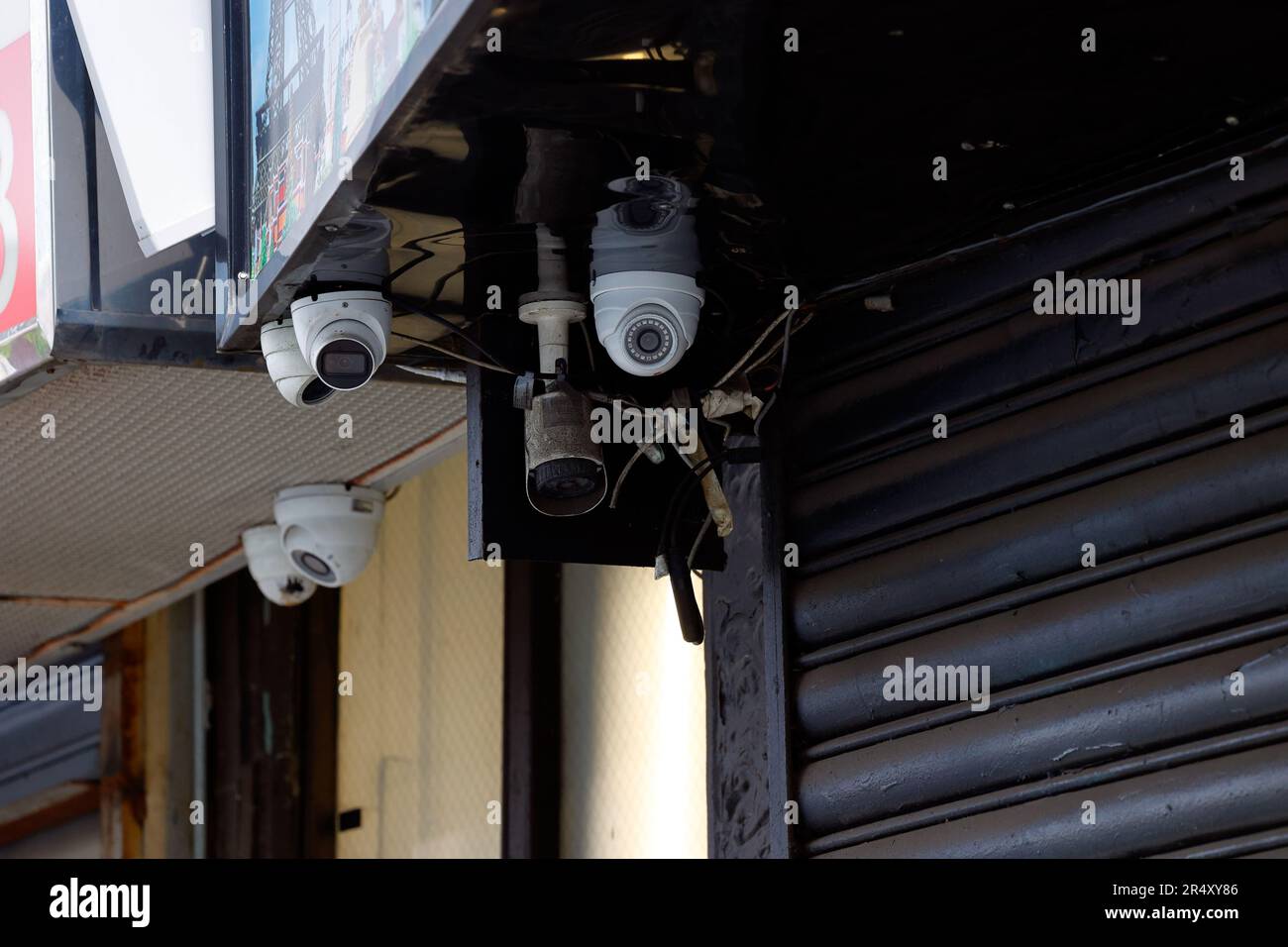 A bunch of CCTV security, close circuit surveillance cameras outside a store pointed in multiple directions toward a public street. Stock Photo