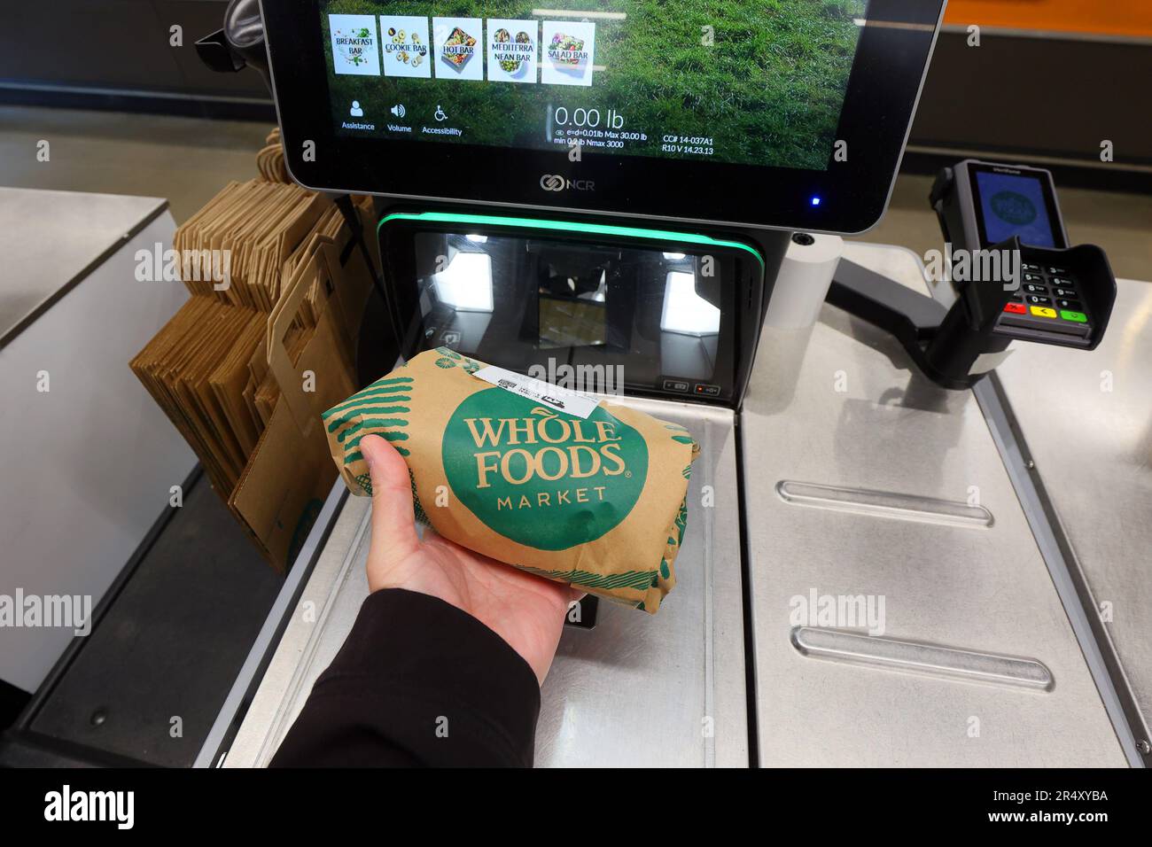 A person scans a grocery item at a Whole Foods Market self checkout station. Stock Photo